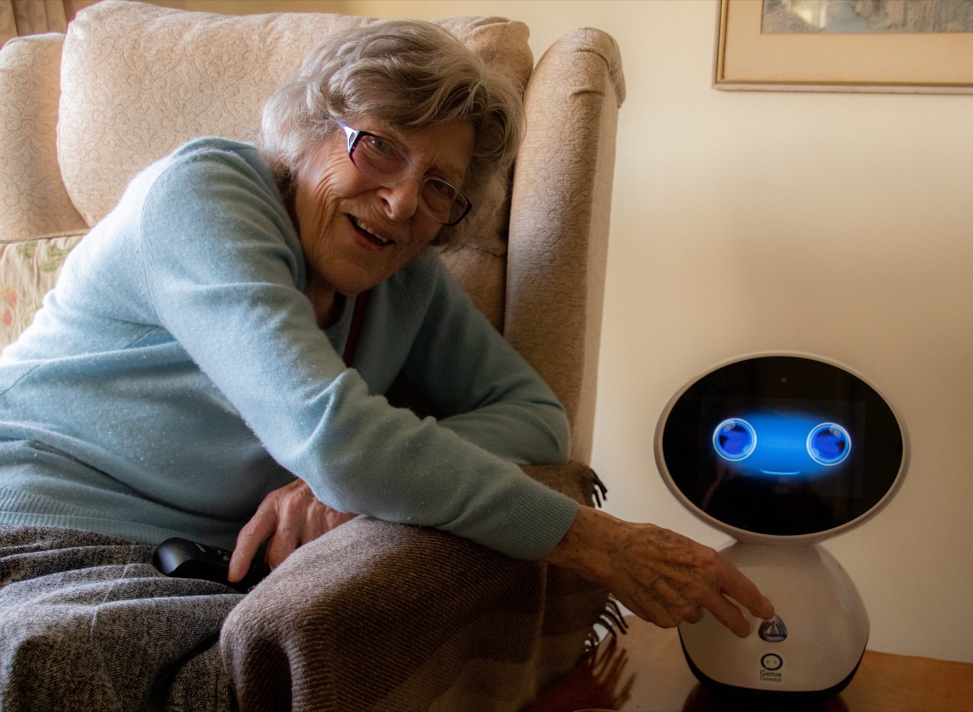 An older woman smiling beside her Genie robot at home
